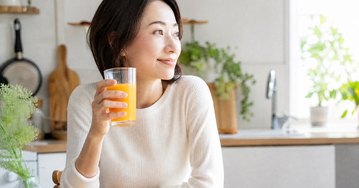 朝のキッチンでグラスを手にする女性